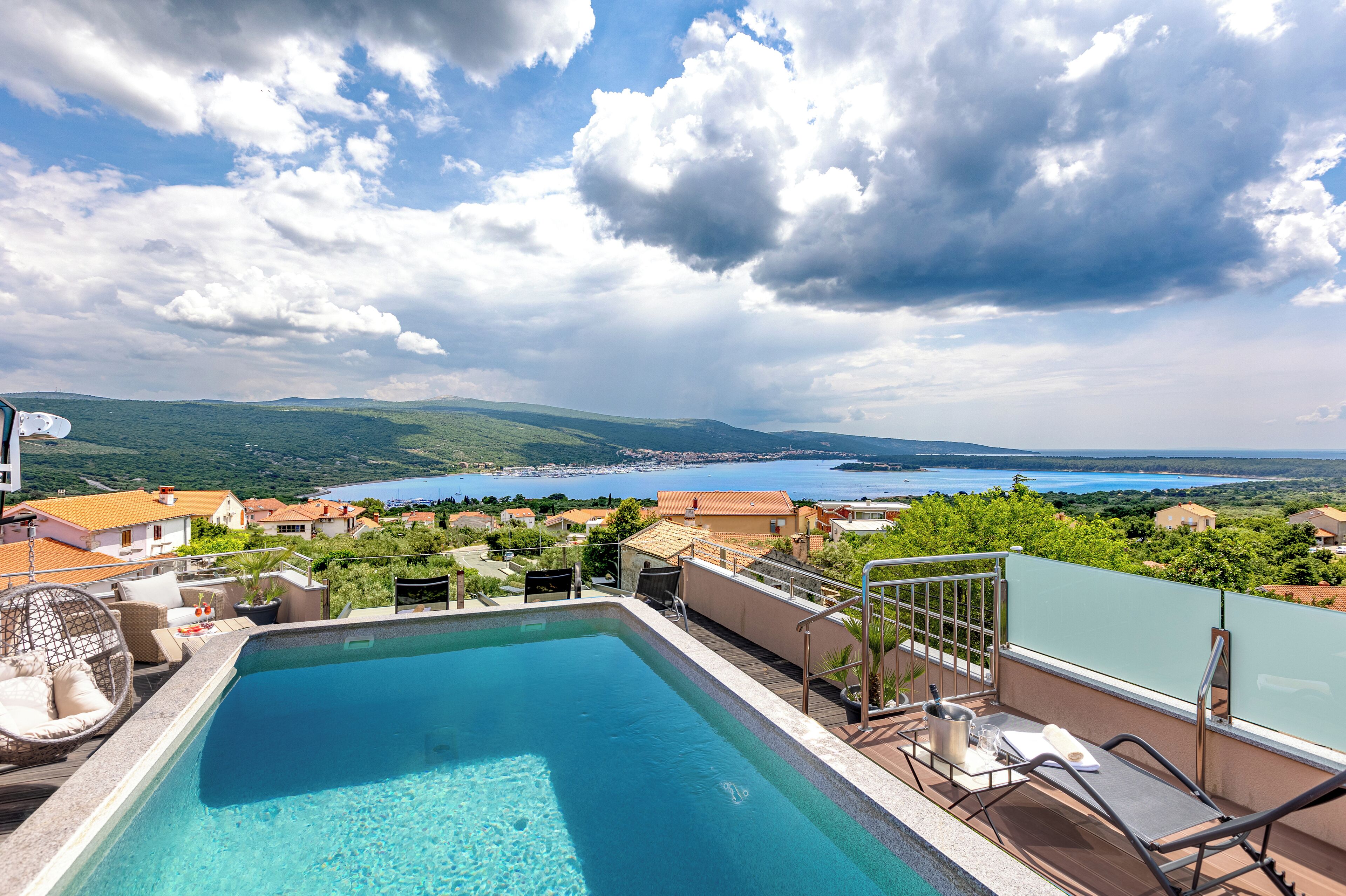 A rooftop pool with a view of a lake and surrounding houses.