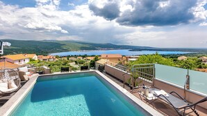 A rooftop pool with a view of a lake and surrounding houses. - Family and child-friendly 5* villa with pool, games and fitness room (KORNIC)