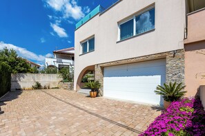 Una casa moderna de dos pisos con garaje, detalles de piedra y entrada pavimentada.