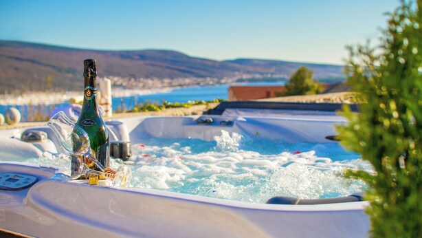 A hot tub with a bottle of champagne, surrounded by a scenic view of a lake and mountains. - Family and child-friendly 5* villa with pool, games and fitness room (KORNIC)