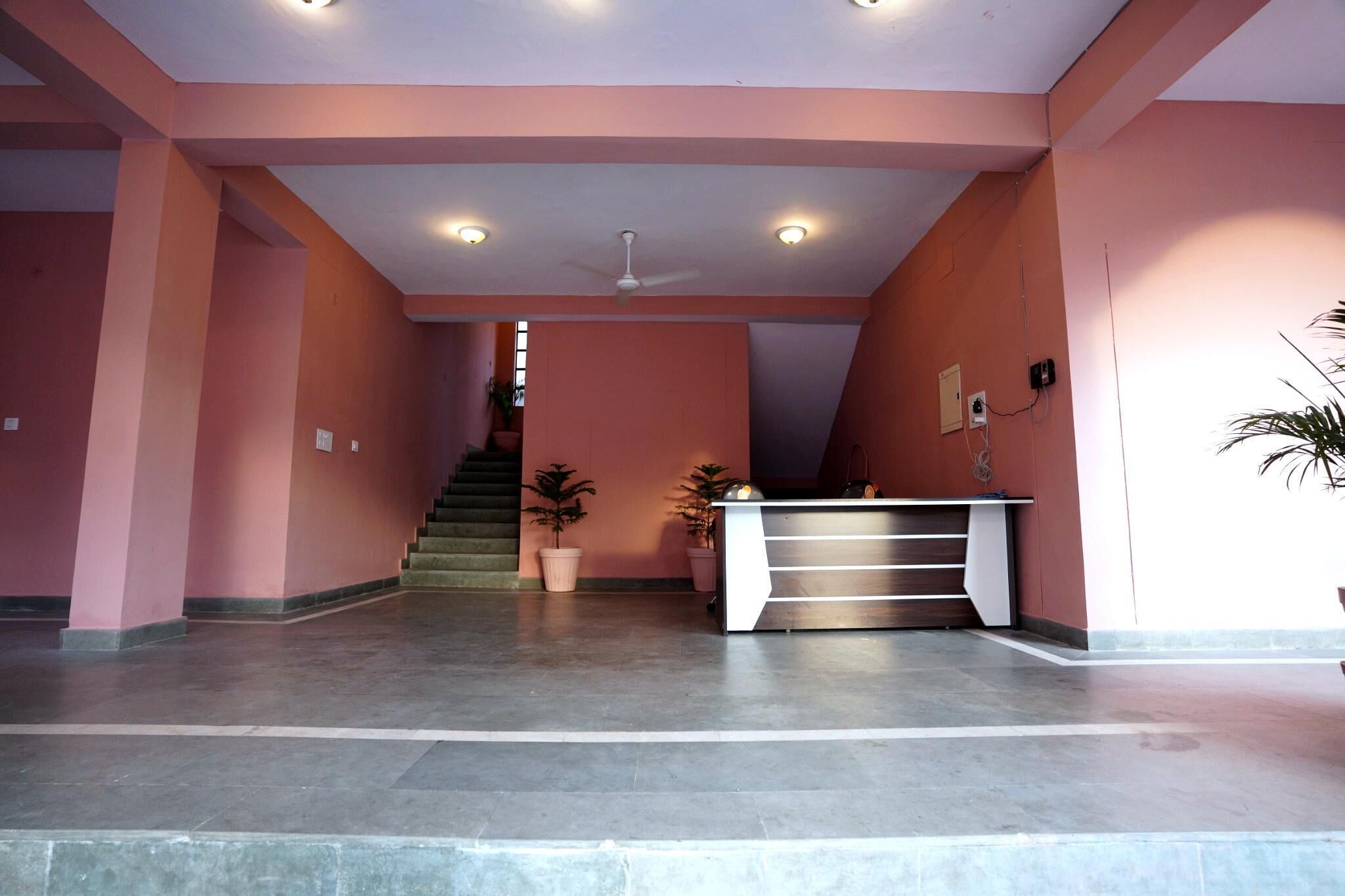 A reception area with a staircase, a ceiling fan, and potted plants.