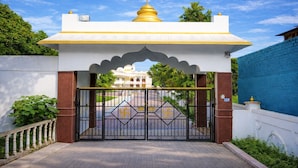 A gated entrance with a traditional archway, a golden dome, and a white building in the background. - Gangabagh by Divine Trails - Hotel Near Har Ki Pauri, Haridwar (Haridwar)