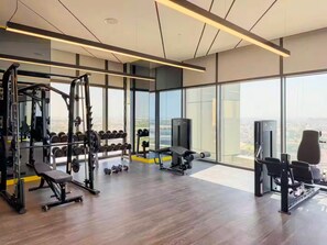 Une salle de sport moderne, dotée d’une variété d’équipements, de grandes fenêtres et offrant une vue sur la ville.