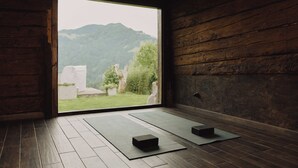 A room with wooden flooring, a large window, and two black mats. - Montenido - Rustic mountain farmhouse with infrared sauna and swimming pond (Oberau)
