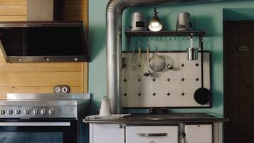 Une cuisine équipée d’une cuisinière en acier inoxydable, d’un four blanc et d’un porte-casseroles suspendu.