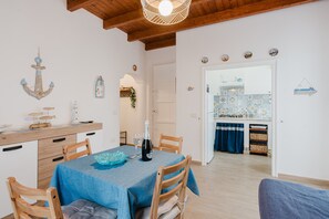 A dining area with a table set for two, wooden chairs, a blue tablecloth, and a bottle of champagne. - Apartment 'Casa Del Pescatore' with Balcony, Wi-Fi and Air Conditioning (Trappeto)