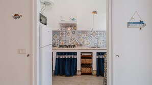 A kitchen with a tiled backsplash, a gas stove, a sink, and blue curtains.