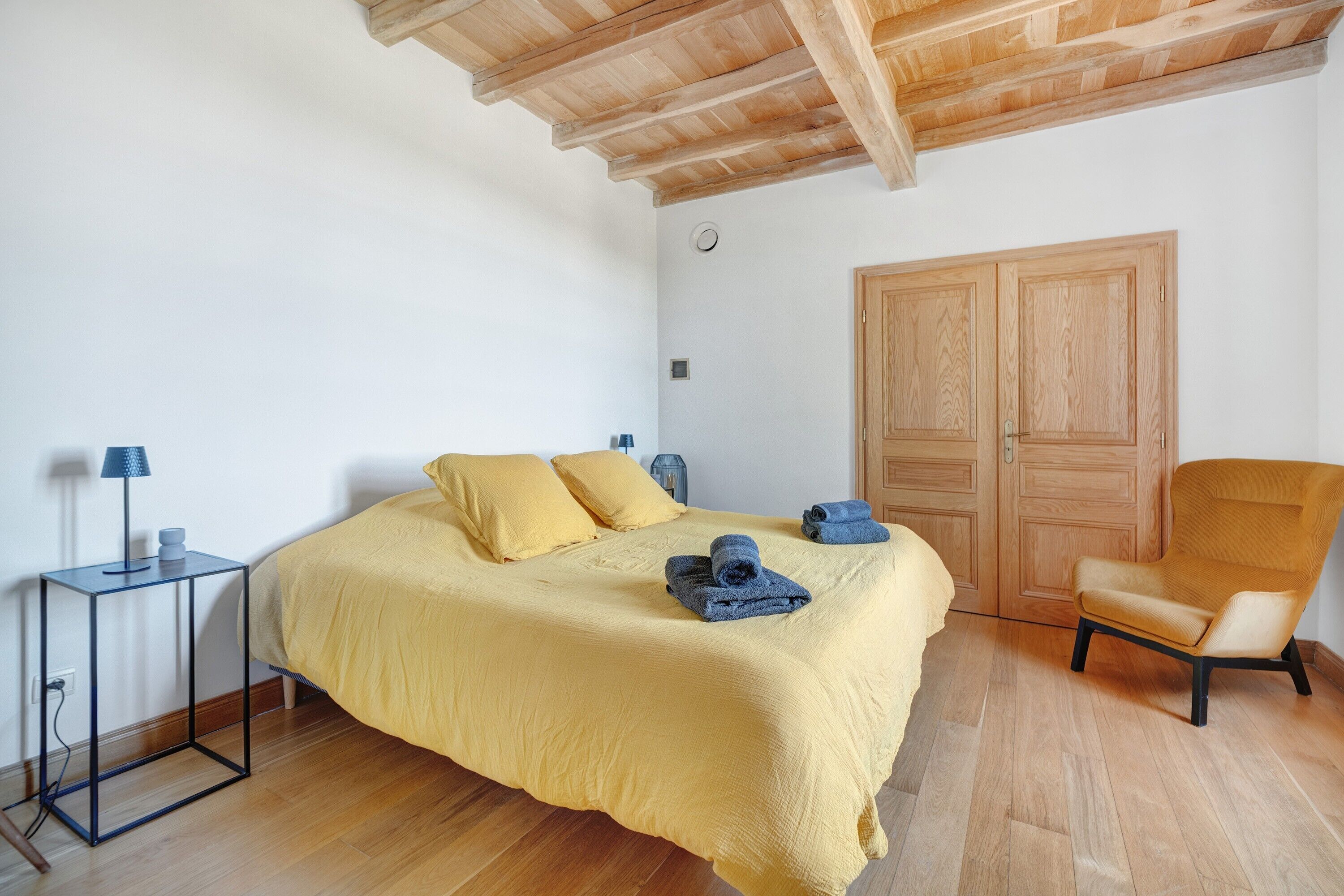 Quarto com cama, cadeira, mesa de cabeceira e guarda-roupa.
