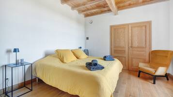 Quarto com cama, cadeira, mesa de cabeceira e guarda-roupa.