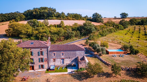 A stone building with a tiled roof, a swimming pool, and a small outdoor seating area. - Casa Lounell: Pool, Spa, Sauna & Games Room in the Tarn Countryside (Graulhet)