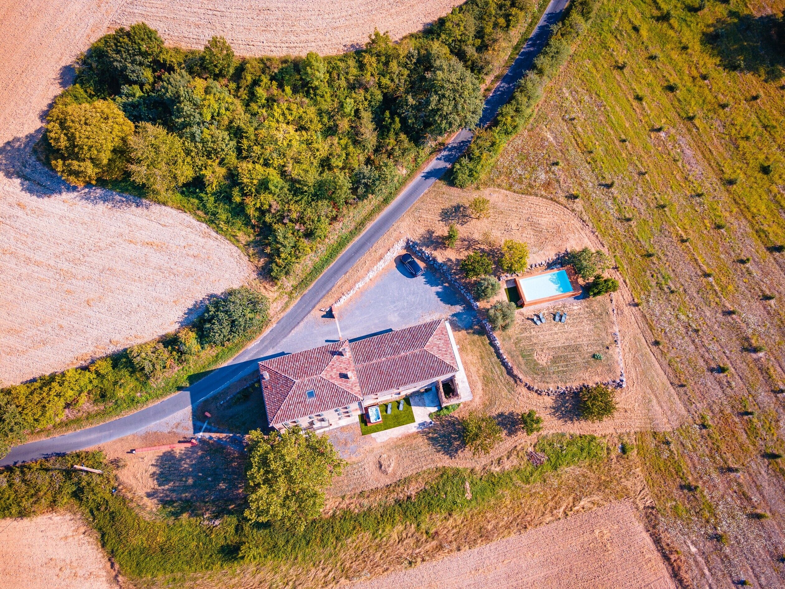 Luchtbeeld van een pand met een groot huis, een zwembad en een oprit.
