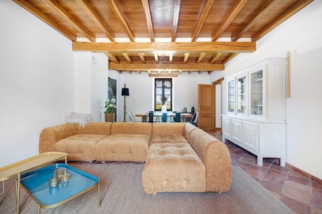 A living room with a sectional sofa, a dining area, and a kitchen with white cabinets.. Casa Lounell: Pool, Spa, Sauna & Games Room in the Tarn Countryside