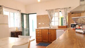 A kitchen with a wooden table, chairs, a sink, and a dishwasher. - Villa GrandVale (Castro Marim)