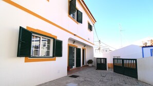 A narrow alleyway with a white building featuring green shutters and a small entrance. - Villa GrandVale (Castro Marim)