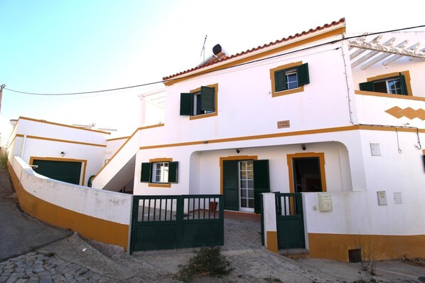 A two-story building with a white facade and green accents, featuring a gated entrance and a staircase leading to the upper floor. - Villa GrandVale (Castro Marim)
