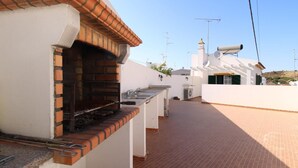 A rooftop with a brick oven, a white wall, and a tiled patio. - Villa GrandVale (Castro Marim)