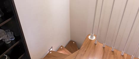 A wooden staircase with a glass cabinet on the left.