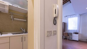 Una cocina con un lavamanos, armarios, un teléfono y una ventana con cortinas.