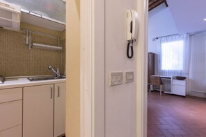 A kitchen with a sink, cabinets, a phone, and a window with curtains. - Santa Croce Cozy Duplex (Firenze)
