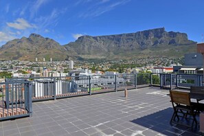 Une terrasse sur le toit offrant une vue sur une montagne et sur le paysage urbain.