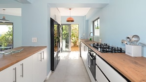 A modern kitchen with a wooden countertop, stainless steel appliances, and a view to the outdoors. - Spacious Family Camps Bay Escape Spectacular Views Pool Garden (Cape Town)