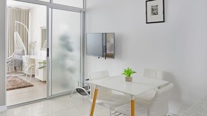 A modern dining area with a white table, chairs, and a small potted plant. - Charming Central Sea Point Haven 50m to Ocean (Cape Town)