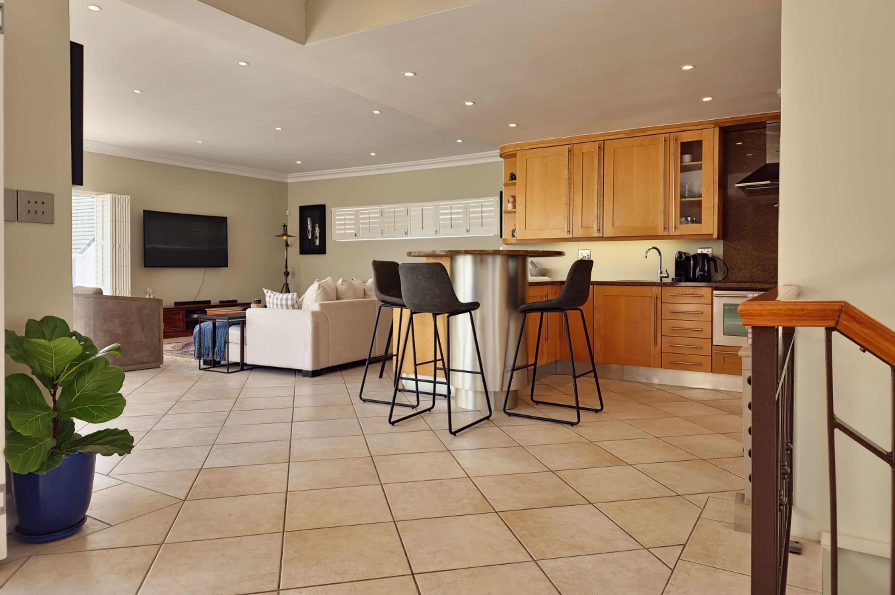 A modern kitchen with wooden cabinets, a bar area, and a seating area with a sofa and chairs.