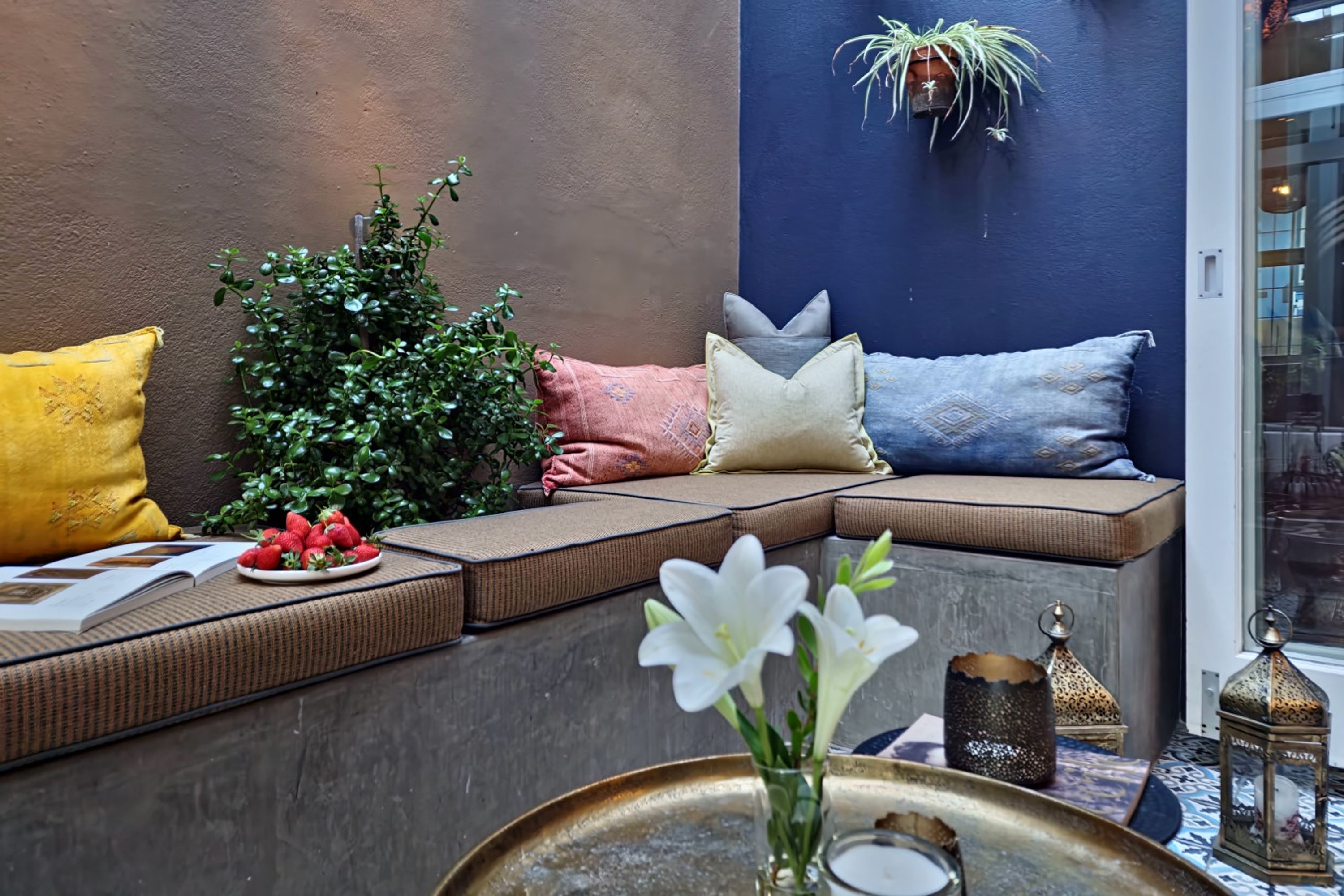 A cozy seating area with cushions, a potted plant, and decorative items.