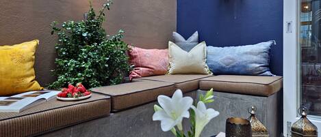 A cozy seating area with cushions, a potted plant, and decorative items.