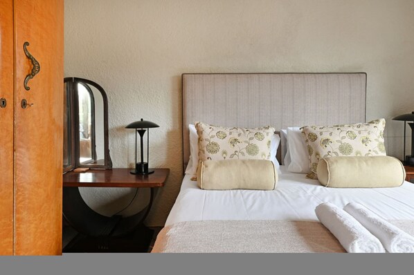 Ein Hotelzimmer mit einem Bett, zwei Kissen, einem Nachttisch mit Lampe und einem Spiegel.