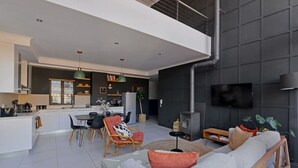 Un espace de vie moderne comprenant une cuisine, un coin repas et un espace détente avec un canapé et des fauteuils.