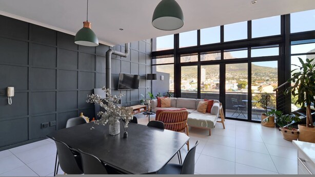 Un salon moderne doté d’une grande fenêtre, d’un coin repas et d’un canapé.