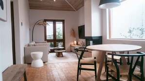 A modern living room with a wooden floor, a round dining table with chairs, a sofa, a coffee table, and a TV. - Serene Oasis Nestled Under Table Mountain (Cape Town)