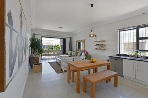 Una cocina moderna con armarios blancos, una mesa de comedor de madera y un ventanal grande.