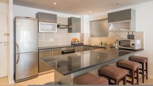 A modern kitchen with a central island, stainless steel appliances, and a microwave. - 6th Floor - 3bed City Center Spacious Secure (Cape Town)