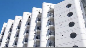 A modern building with cylindrical white towers, balconies with black railings, and circular windows. - The Flamingo One Bed Sea Point Promenade (Cape Town)