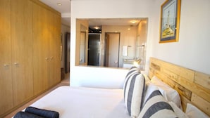 A hotel room with a large bed, wooden wardrobe, and a mirror reflecting the room. - Upmarket 2bed City Retreat Close to V A Waterfront (Cape Town)