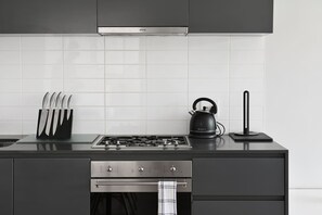 A modern kitchen with a gas stove, a kettle, and a knife block. - Secure 2bed Green Point Retreat Rooftop Pool BBQ (Cape Town)