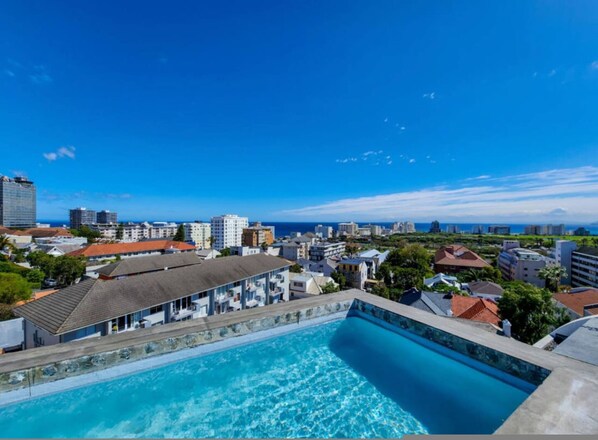 A swimming pool with a view of a cityscape and the ocean. - Secure 2bed Green Point Retreat Rooftop Pool BBQ (Cape Town)