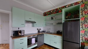 A kitchen with light green cabinets, a stainless steel refrigerator, and a wooden countertop. - Charming 2-bed Central Green Point Stadium (Cape Town)