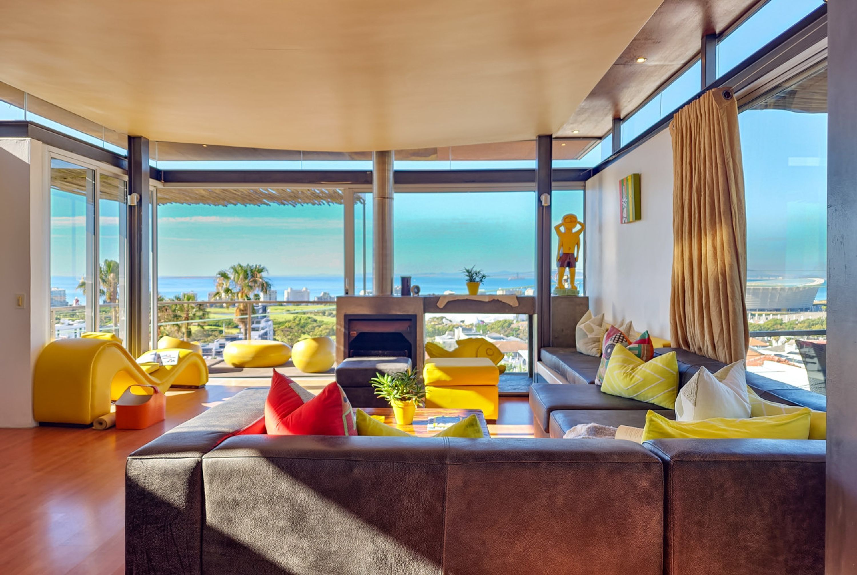 A modern living room with a large sofa, yellow bean bag chairs, and a fireplace.
