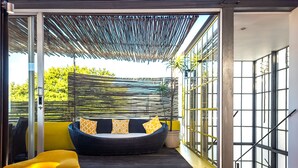 A modern interior with a glass door leading to an outdoor area, a black sofa with patterned cushions, and a yellow chair. - Ocean Views Open Plan Pool 3 Bed (Cape Town)