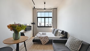 A modern hotel room with a bed, a sofa, a dining table, and a TV. - Modern Apt Co-working East City (Cape Town)