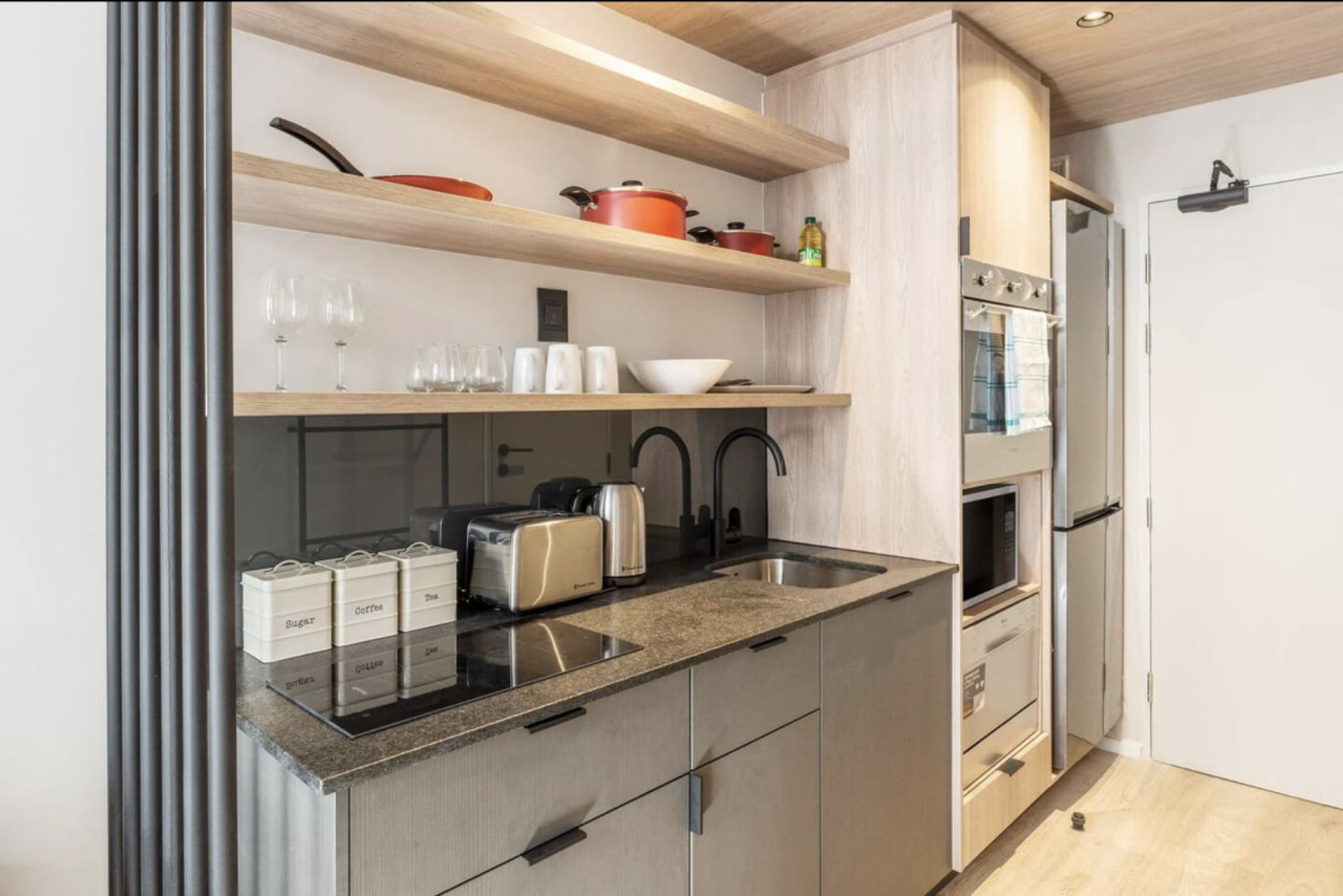 Een moderne keuken met roestvrijstalen apparatuur, houten planken en een granieten aanrecht.