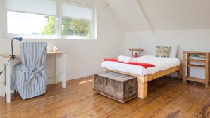 A bedroom with a loft bed, a desk, a chair, and a wooden chest. - Green Point Peaceful Retreat Off-grid (Cape Town)