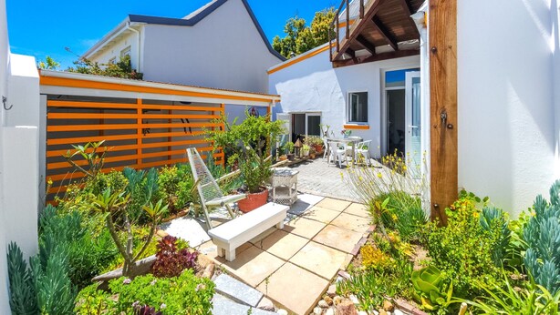 A modern house with a patio area, outdoor furniture, and a variety of plants. - Green Point Peaceful Retreat Off-grid (Cape Town)