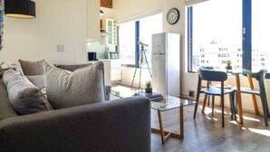 Un salon moderne avec un canapé, une table basse en verre et un coin repas comprenant des chaises et une table.