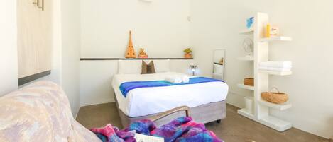 A bedroom with a bed, a bedside table, a chair, a bookshelf, and a wardrobe.
