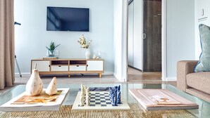 Un salon équipé d’un téléviseur à écran plat, d’une console en bois, d’un jeu d’échecs et d’un canapé.