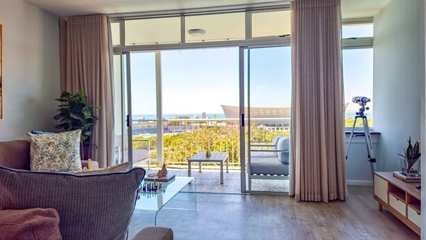 Un salon moderne avec un canapé, une table basse et un balcon offrant une vue agréable.